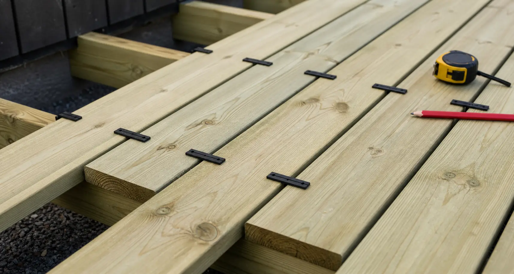 Pressure-treated deck boards with consistent spacers between the boards during installation